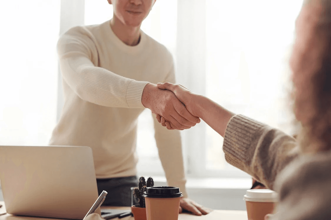 Une poignée de main entre deux personnes à travers un bureau